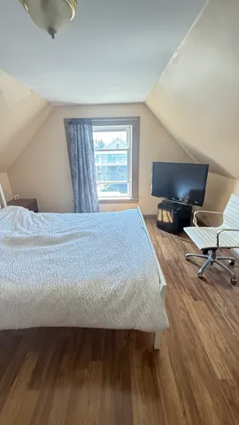 a bedroom with a bed a rug and wooden floor