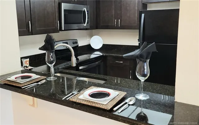a kitchen with kitchen island granite countertop a sink and a refrigerator