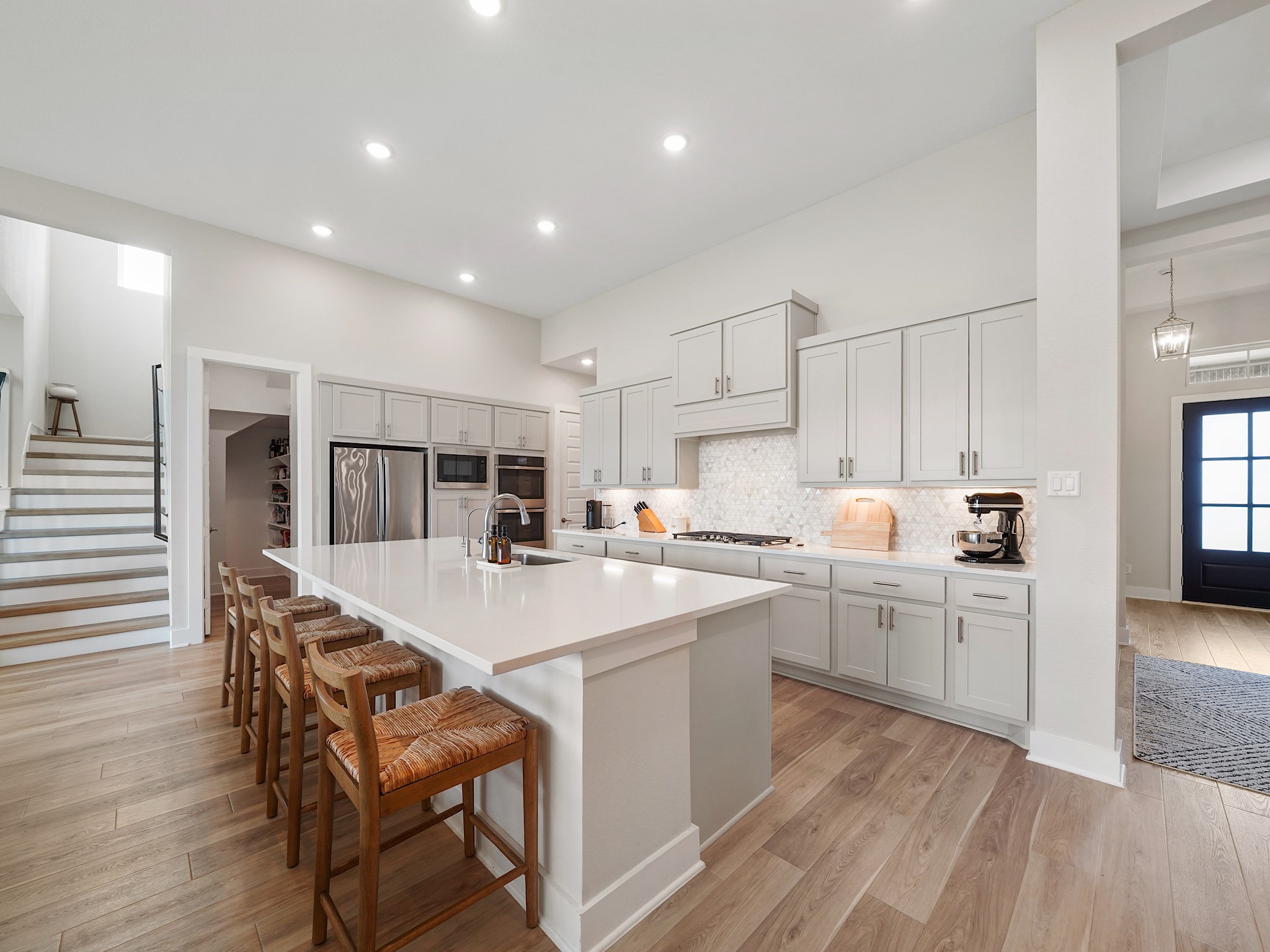 5802 Emerald Ranch Lane Fulshear, TX 77441 - Photo 10 of 45 Designed with both style and function in mind, the chef-inspired kitchen features quartz countertops, double ovens, a gas cooktop, premium stainless steel appliances, and an expansive island overlooking the living area.