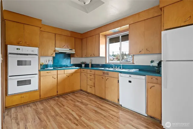 a kitchen with cabinets wooden floor and stainless steel appliances