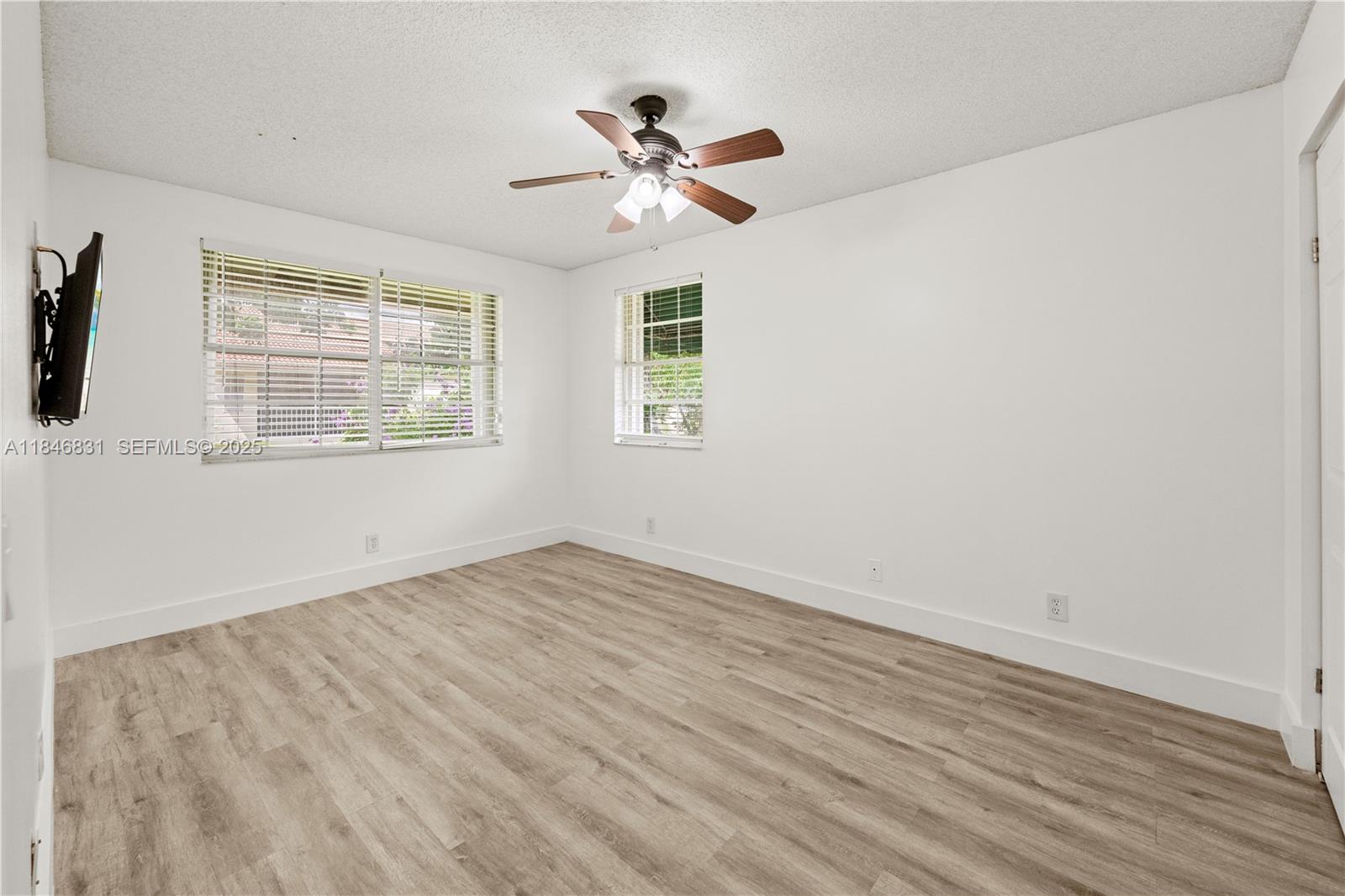6603 Via Regina, Unit 50 Boca Raton, FL 33433 - Photo 30 of 48 an empty room with wooden floor fan and windows
