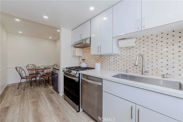 a kitchen with granite countertop a sink a stove and chairs