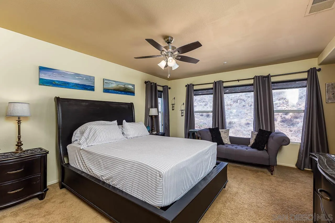 2477 Fallbrook Place Escondido, CA 92027 - Photo 18 of 28 a bedroom with a bed a couch and a chandelier