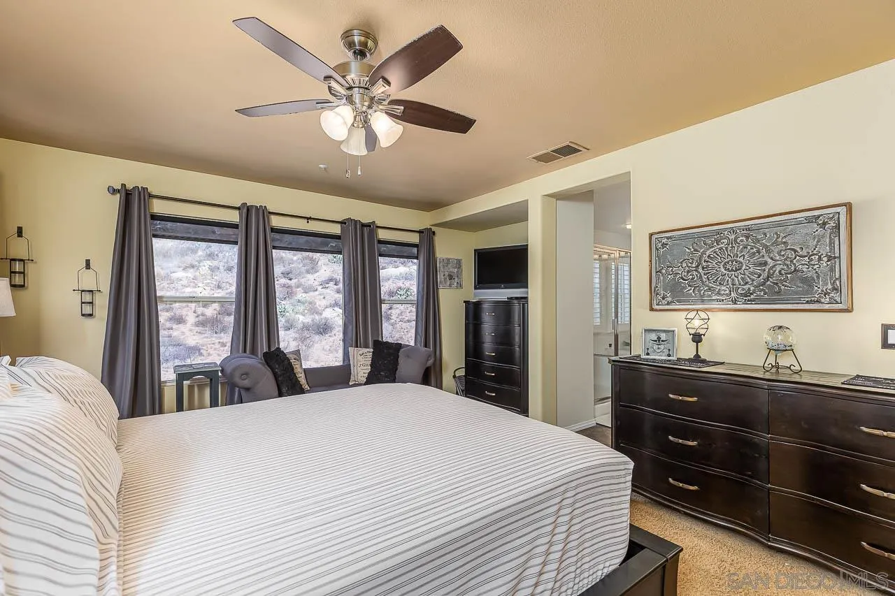 2477 Fallbrook Place Escondido, CA 92027 - Photo 19 of 28 a bedroom with a large bed and a flat tv screen on dresser