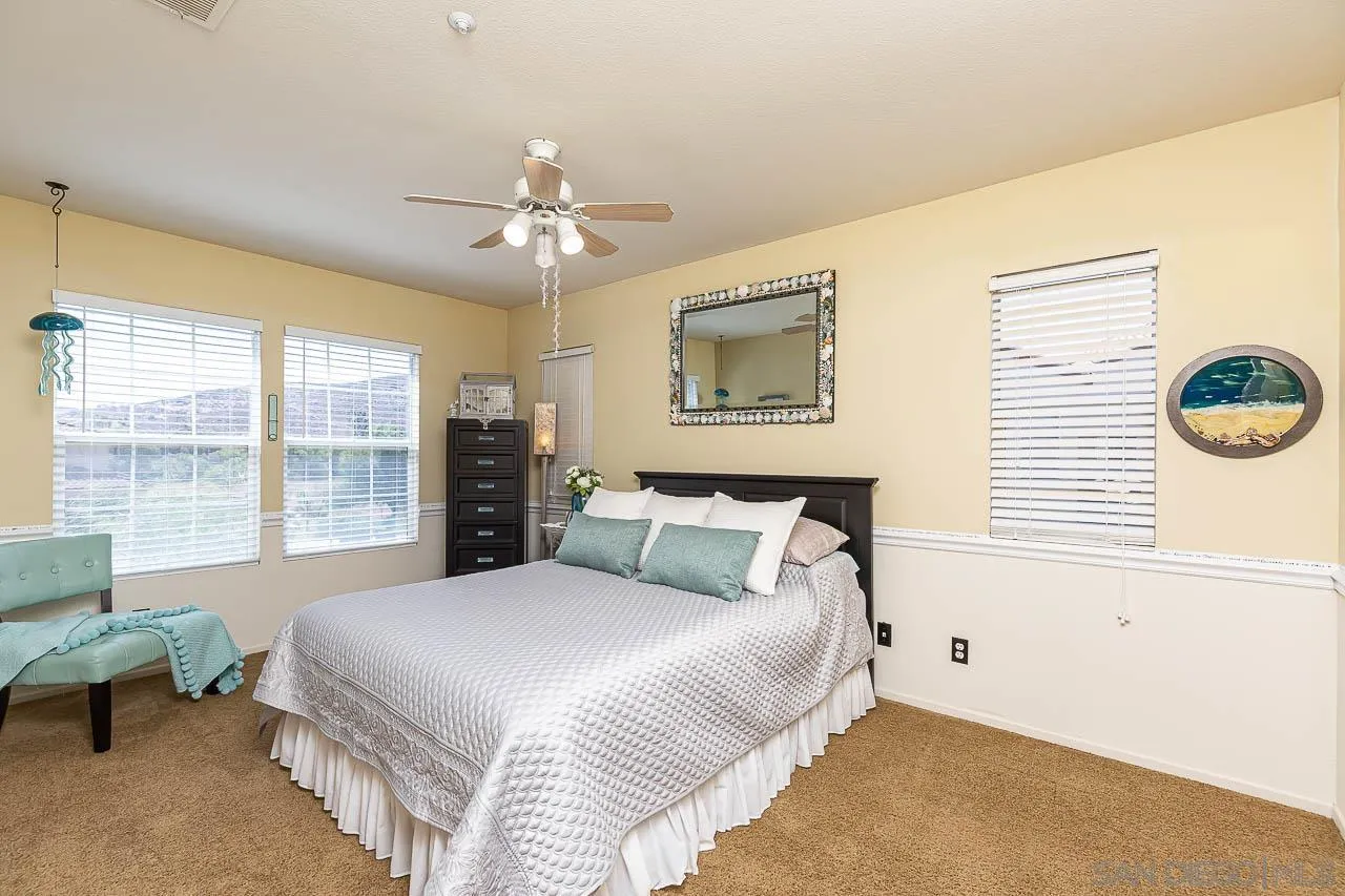 2477 Fallbrook Place Escondido, CA 92027 - Photo 22 of 28 a bedroom with a large bed and a chandelier