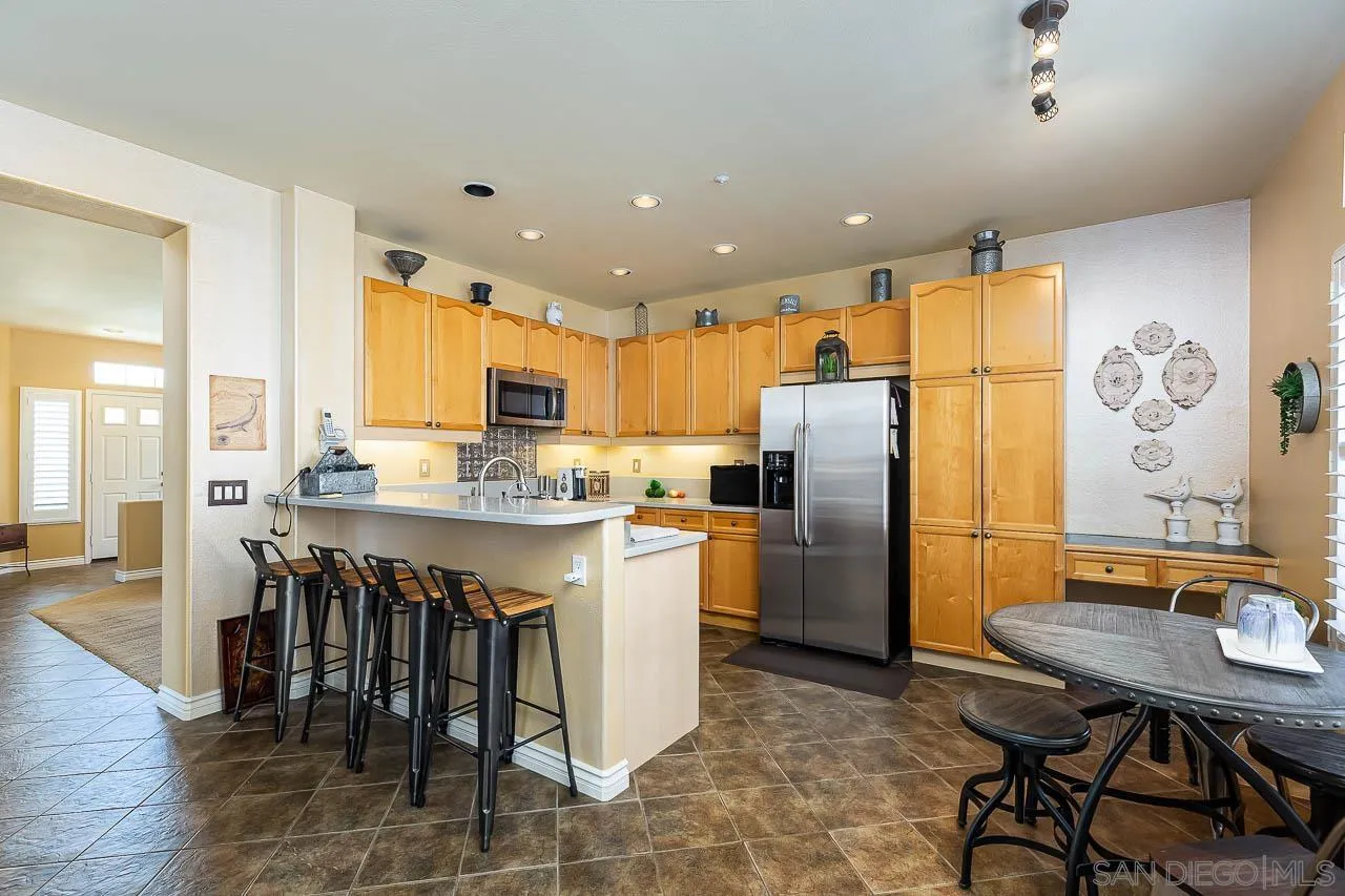 2477 Fallbrook Place Escondido, CA 92027 - Photo 8 of 28 a kitchen with stainless steel appliances granite countertop a table chairs sink and refrigerator