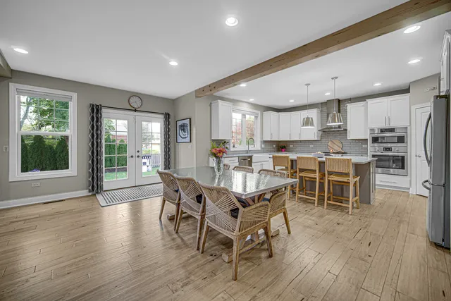 a kitchen with stainless steel appliances a dining table chairs and wooden floor