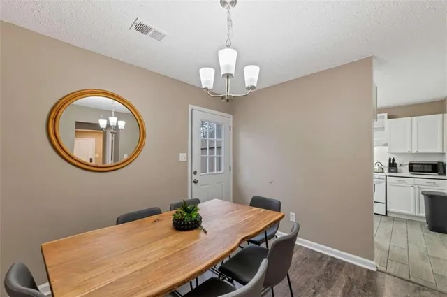 a dining room with wooden floor a chandelier a wooden table and chairs