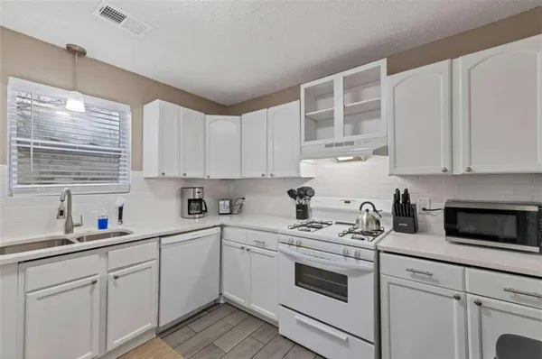 a kitchen with cabinets appliances a sink and a window