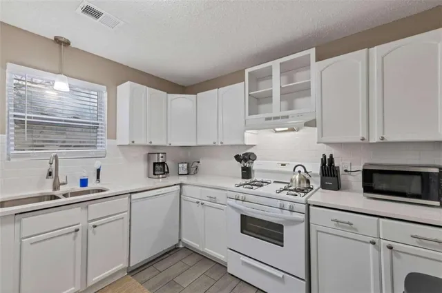 a kitchen with cabinets appliances a sink and a window
