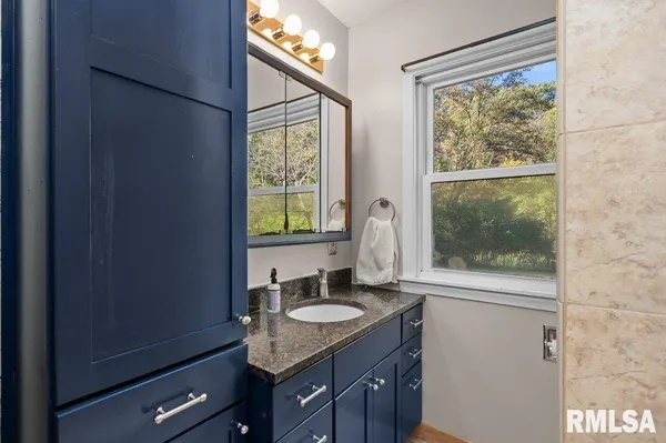 a bathroom with a granite countertop sink and a window