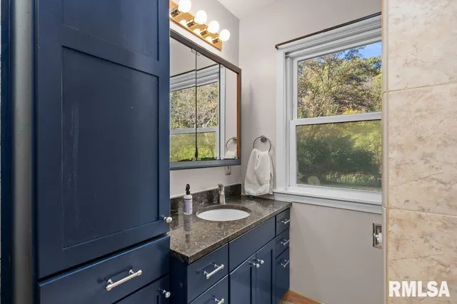 a bathroom with a granite countertop sink and a window