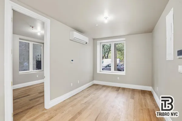 a view of an empty room with wooden floor and a window