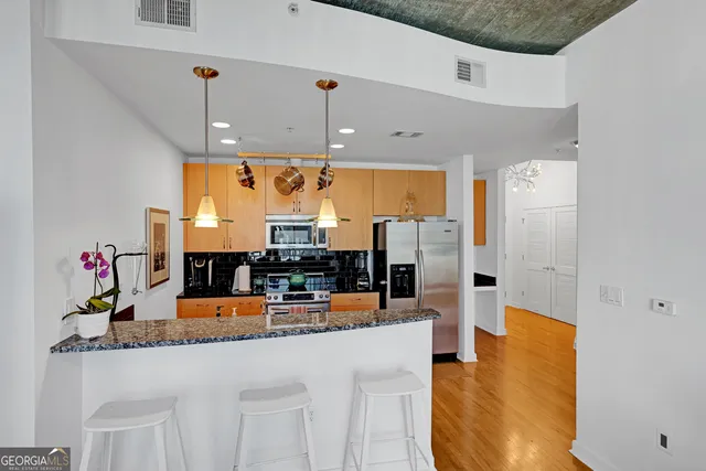 a kitchen with stainless steel appliances kitchen island granite countertop a refrigerator and microwave