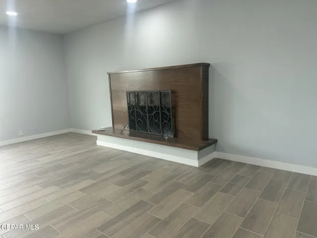 an empty room with wooden floor fire place and windows