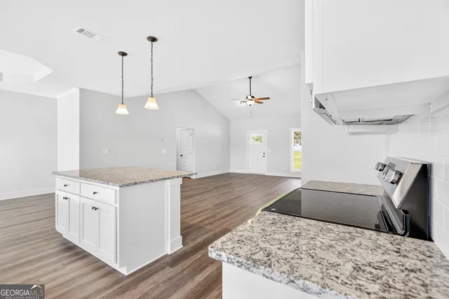 a kitchen with stainless steel appliances granite countertop a sink a stove and a wooden floors