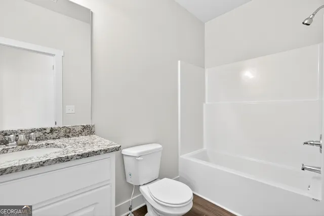 a bathroom with a granite countertop toilet a sink and a bathtub