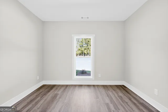 an empty room with wooden floor and window