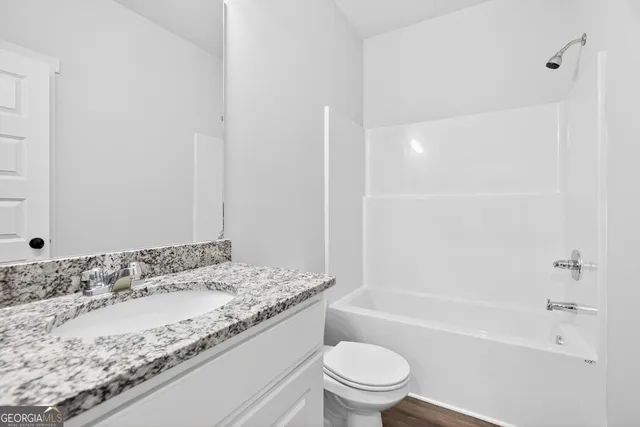 a bathroom with a granite countertop sink a toilet and bathtub