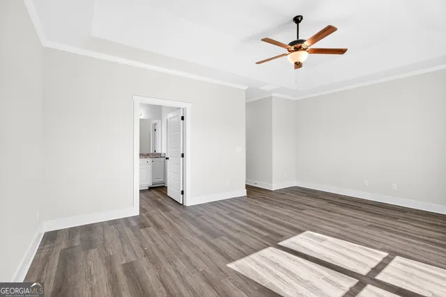 an empty room with wooden floor and a ceiling fan