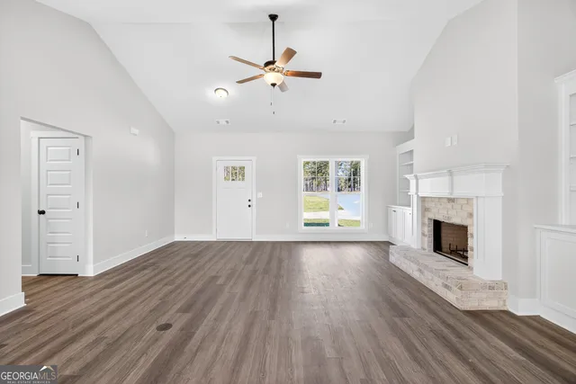an empty room with wooden floor fireplace and windows