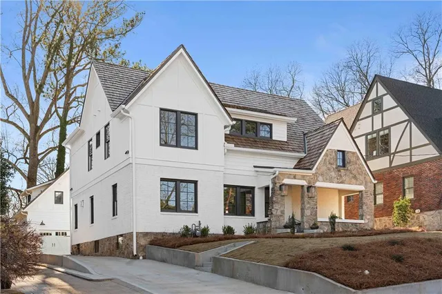 a view of a white house with large windows and a table and chairs