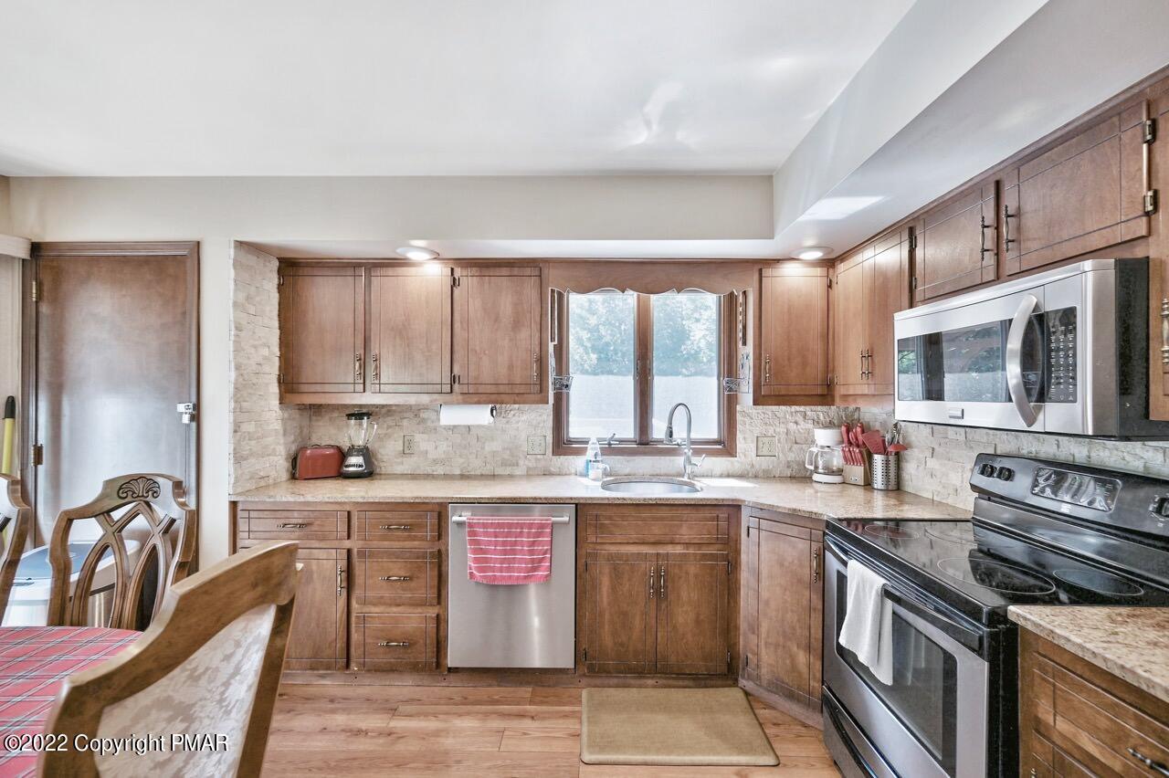 134 Moseywood Road Lake Harmony, PA 18624 - Photo 13 of 70 a kitchen with stainless steel appliances granite countertop a stove top oven a sink dishwasher a dining table and chairs with wooden floor