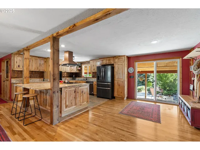 a kitchen with stainless steel appliances kitchen island granite countertop a stove a refrigerator a sink and white cabinets with wooden floor