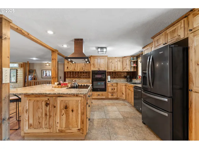 a kitchen with kitchen island a counter top space a refrigerator and cabinets