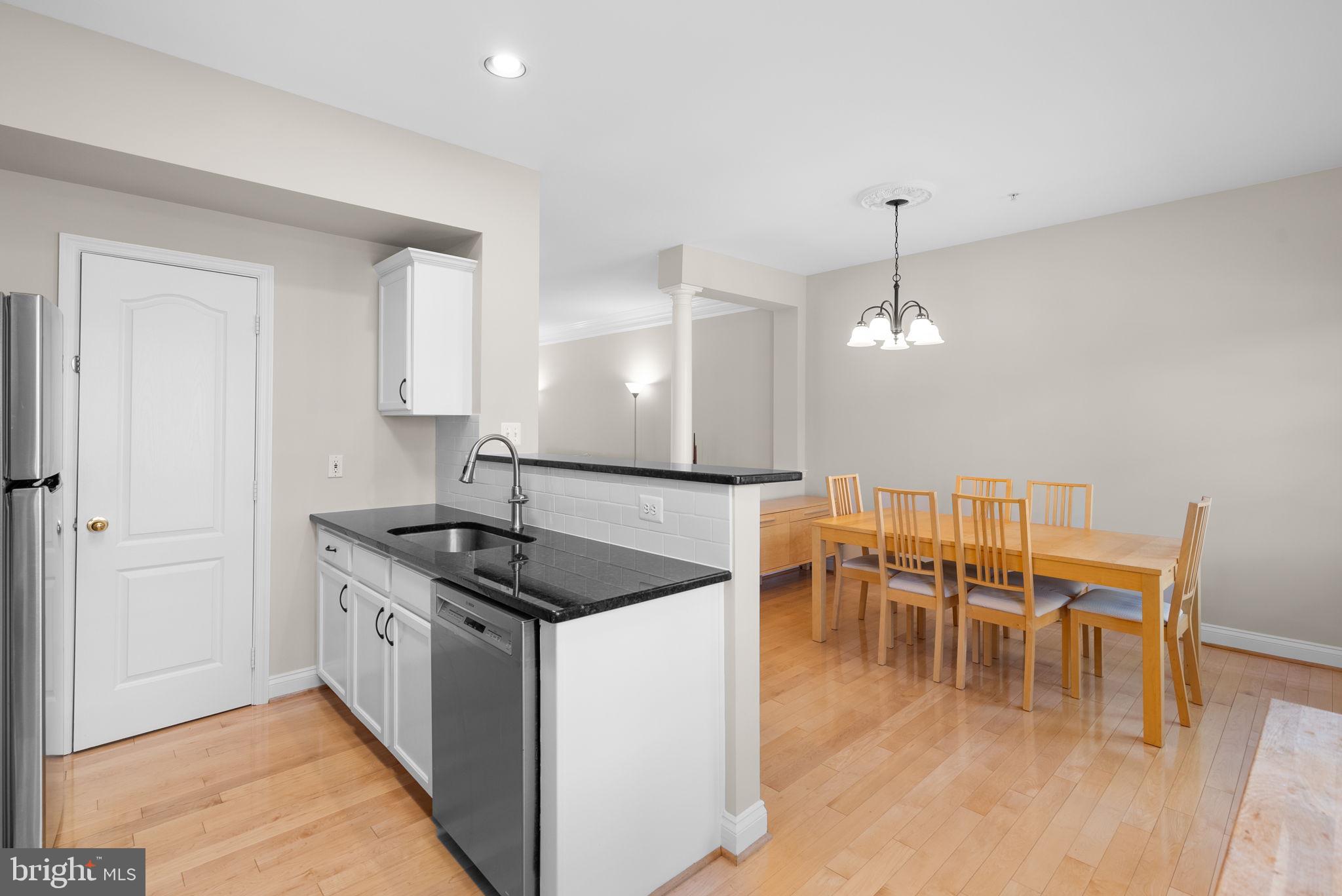 215 Poplar Spring Road Rockville, MD 20850 - Photo 11 of 30 a kitchen with stainless steel appliances granite countertop a stove a sink a dining table and chairs with wooden floor