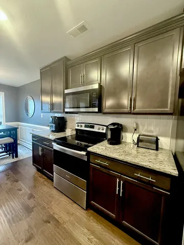 a large kitchen with stainless steel appliances granite countertop a stove a sink and a microwave