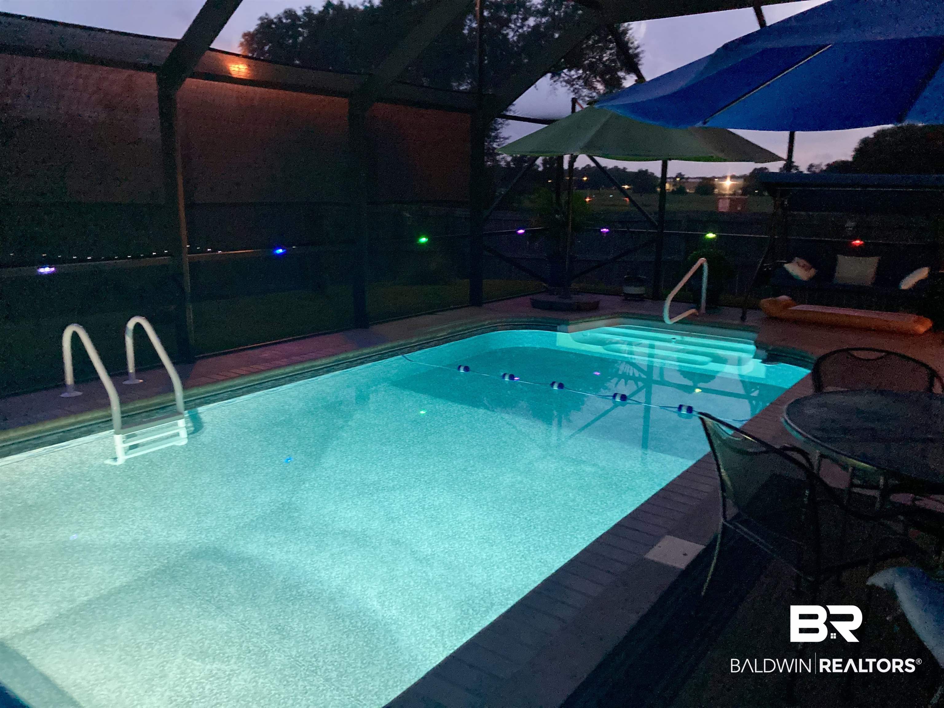 1676 Abbey Loop Foley, AL 36535 - Photo 27 of 31 Screened-in pool area featuring a rectangular pool with integrated steps, handrails, and surrounding brick-style coping