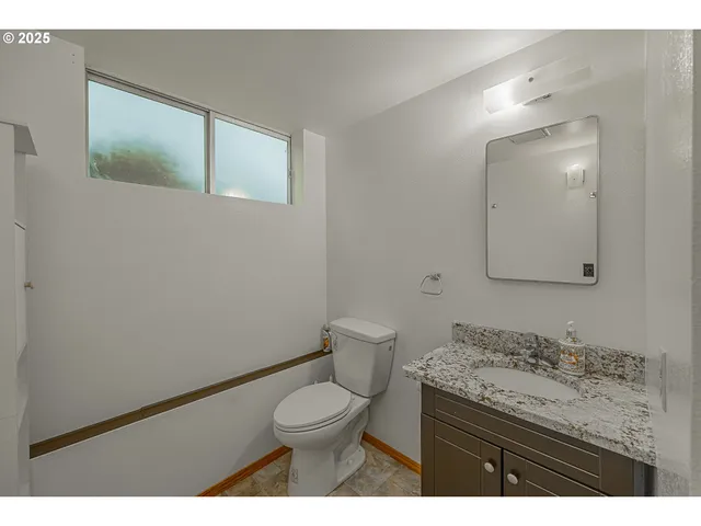 a bathroom with a granite countertop toilet a sink and a mirror