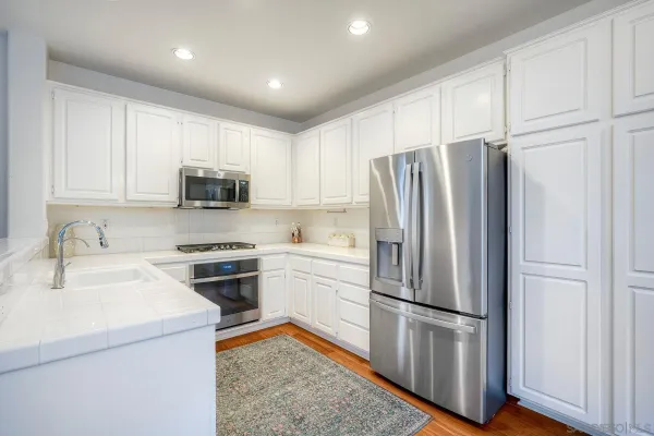 a kitchen with stainless steel appliances white cabinets and a refrigerator