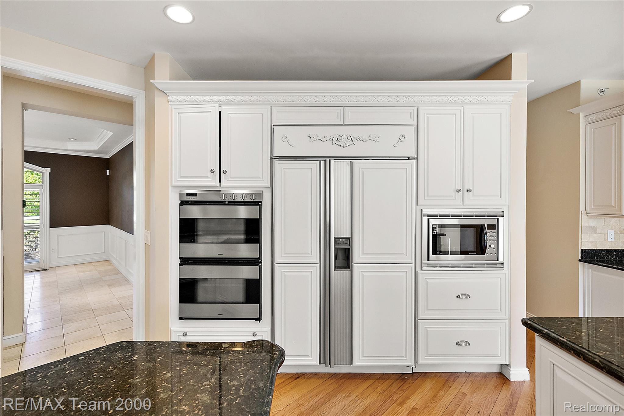 630 Sheldon Court Rochester, MI 48306 - Photo 29 of 94 Kitchen featuring built in appliances, white cabinetry, wainscoting, dark stone counters, and recessed lighting