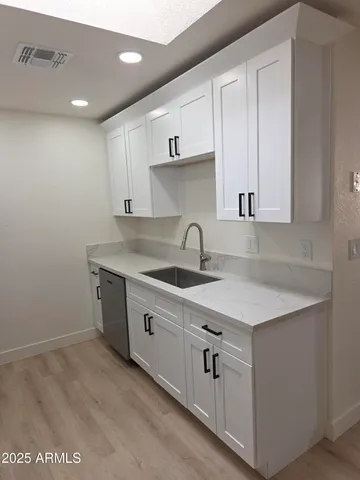 a kitchen with white cabinets sink and dishwasher