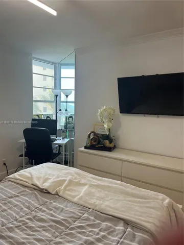 a bedroom with a bed and a flat tv screen on dresser
