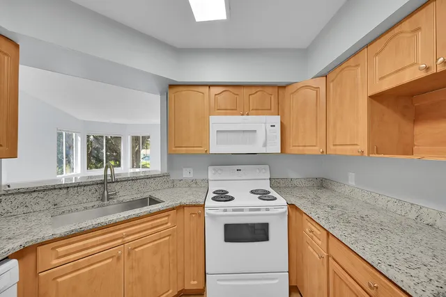 a kitchen with granite countertop cabinets sink and white appliances