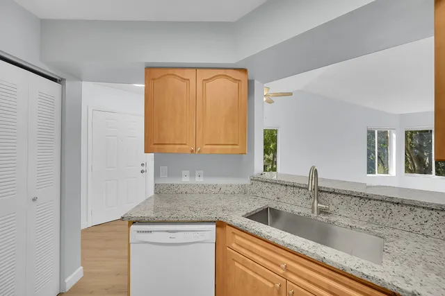 a kitchen with granite countertop a sink a window and cabinets