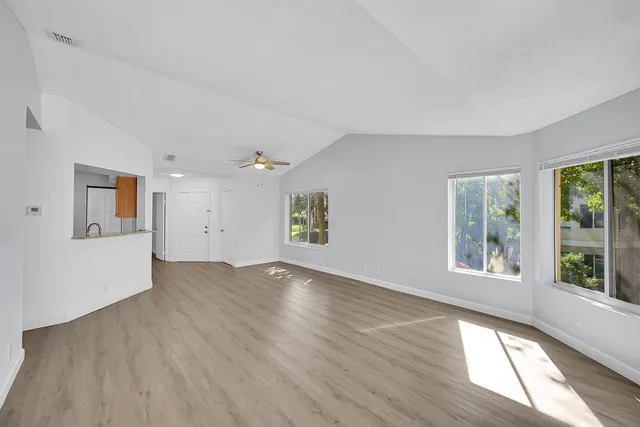 a view of an empty room with wooden floor and a window