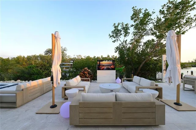 a view of a patio with couches table and chairs under an umbrella with a fire pit