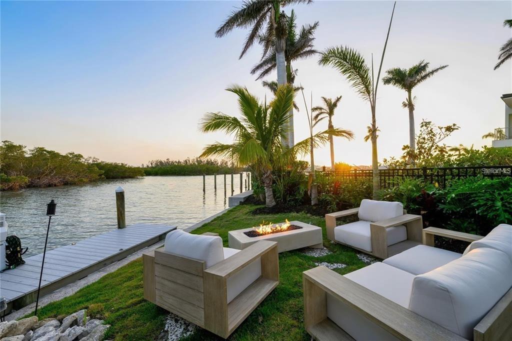 1406 Tangier Way Sarasota, FL 34239 - Photo 23 of 58 a view of a patio with couches chairs and a table and chairs with wooden floor and lake view