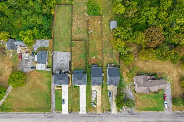 an aerial view of residential houses with outdoor space and trees