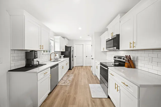 a kitchen with granite countertop white cabinets sink and stainless steel appliances