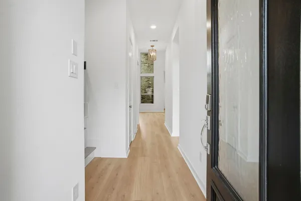 a view of a hallway with wooden floor and a bathroom