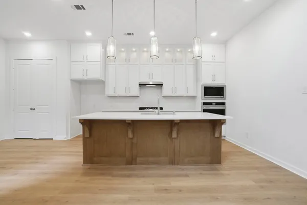 a large kitchen with kitchen island white cabinets and stainless steel appliances