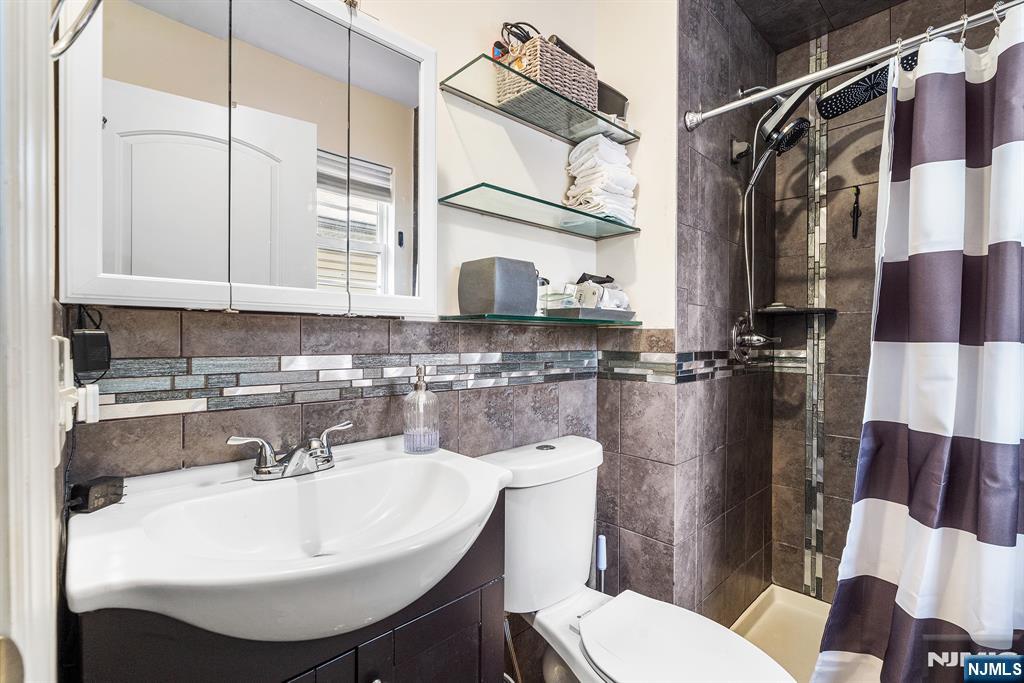 128 Baltimore Avenue Hillside, NJ 07205 - Photo 22 of 50 a bathroom with a sink a toilet and a mirror