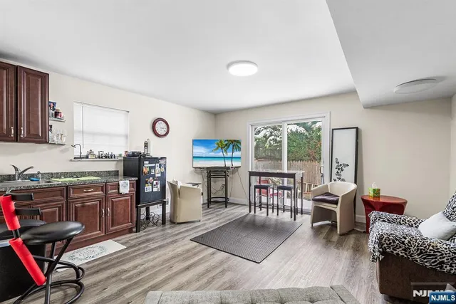 a open kitchen with stainless steel appliances granite countertop a stove top oven a refrigerator a dining table and chairs with wooden floor