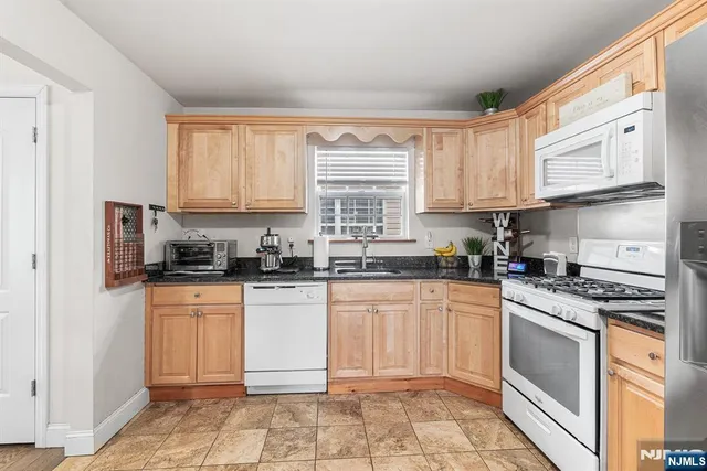 a kitchen with granite countertop white cabinets and white appliances