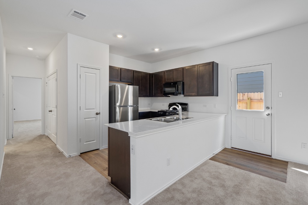 230 Gabbro Gardens Maxwell, TX 78656 - Photo 8 of 24 a view of a kitchen with a sink and a refrigerator